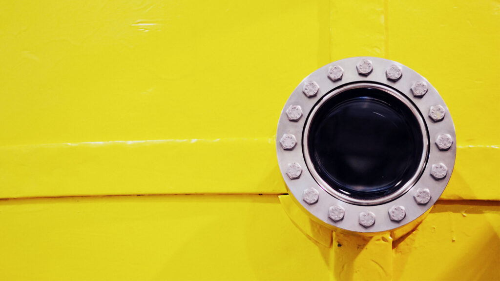 A black port-hole inset into a bright yellow wall of a spectrometer