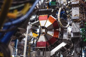 A symmetrical red-and-silver detector made up of interconnected pieces aligning around a central chamber