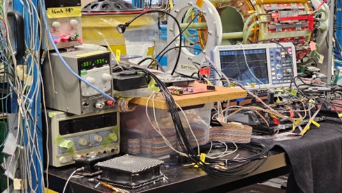 An assembly of multi-coloured wires and an oscilloscope on a lab bench